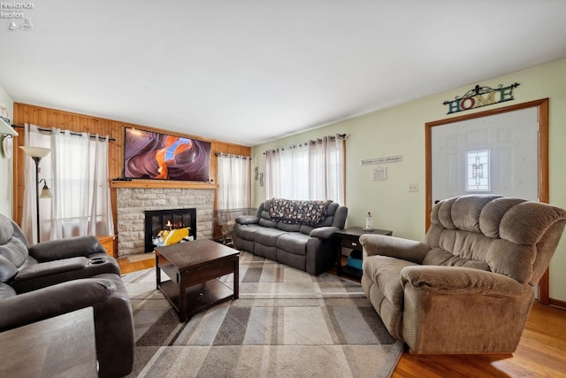 living room with plenty of natural light, a stone fireplace, and light hardwood / wood-style flooring