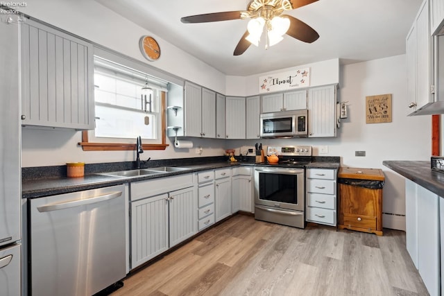 kitchen with gray cabinets, sink, ceiling fan, stainless steel appliances, and light hardwood / wood-style flooring