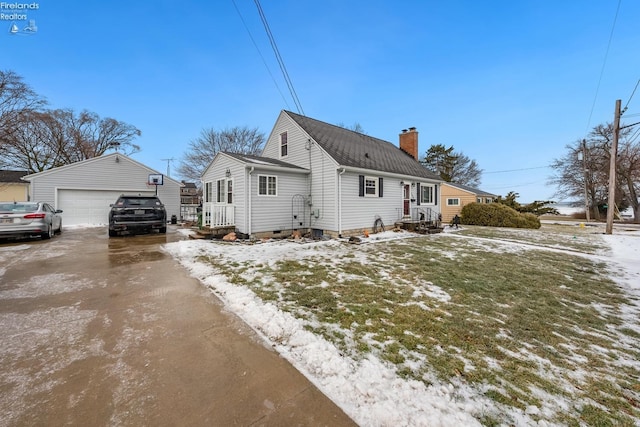 snow covered property featuring a garage and an outbuilding