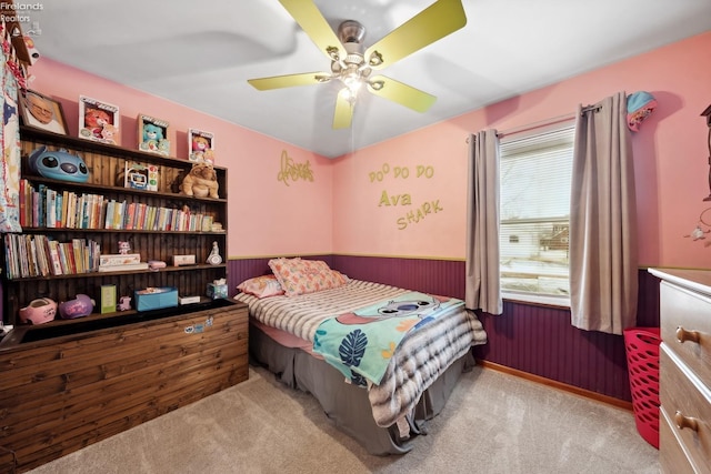 carpeted bedroom with ceiling fan and wood walls