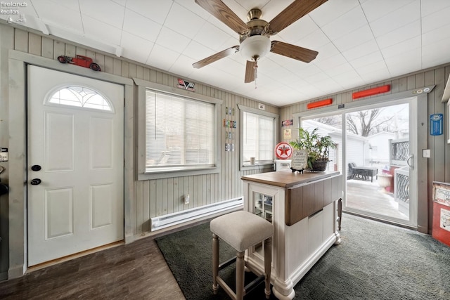 interior space featuring dark wood-type flooring, ceiling fan, and a baseboard heating unit