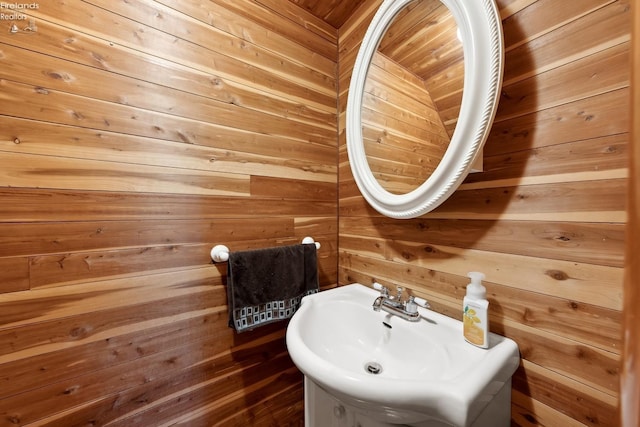 bathroom featuring wooden walls and sink