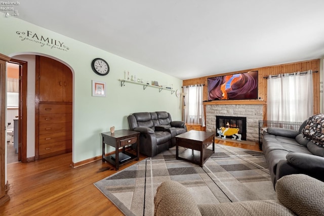 living room with hardwood / wood-style flooring, plenty of natural light, and a stone fireplace