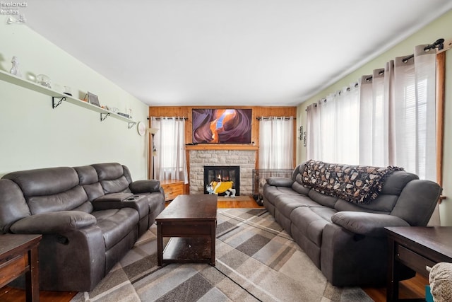 living room featuring a stone fireplace and wooden walls