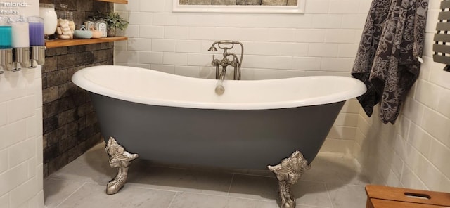 bathroom with tile patterned floors, a tub to relax in, and tile walls