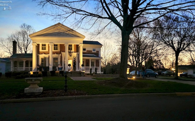 neoclassical / greek revival house featuring a lawn and a porch