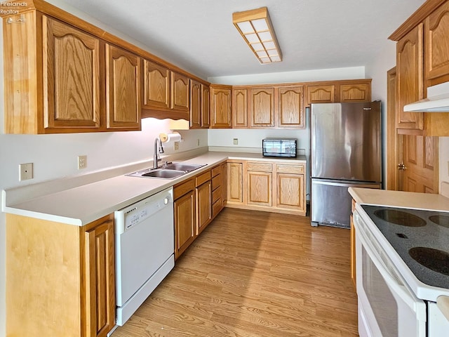 kitchen with white appliances, brown cabinetry, light countertops, light wood-style floors, and a sink