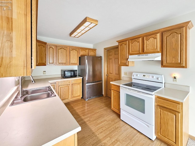 kitchen featuring white electric stove, freestanding refrigerator, a sink, black microwave, and under cabinet range hood