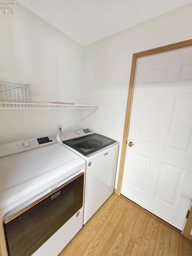 laundry area featuring light wood-type flooring, laundry area, and washer and clothes dryer