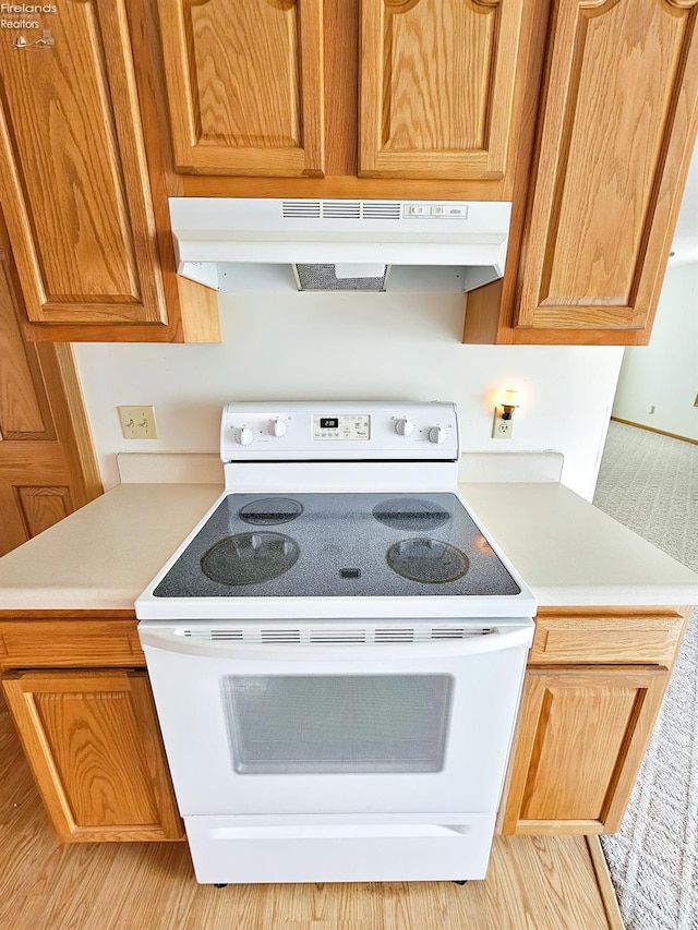 kitchen featuring under cabinet range hood, white electric stove, and light countertops