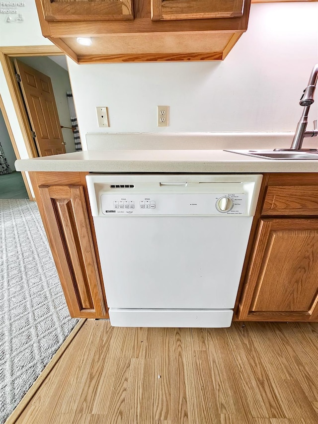 interior space with a sink, light wood-style floors, light countertops, dishwasher, and brown cabinetry