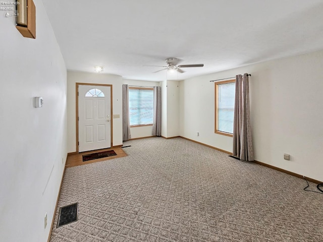 entryway with carpet flooring, ceiling fan, visible vents, and baseboards