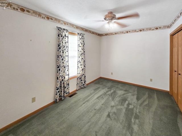 carpeted spare room featuring baseboards, visible vents, and ceiling fan