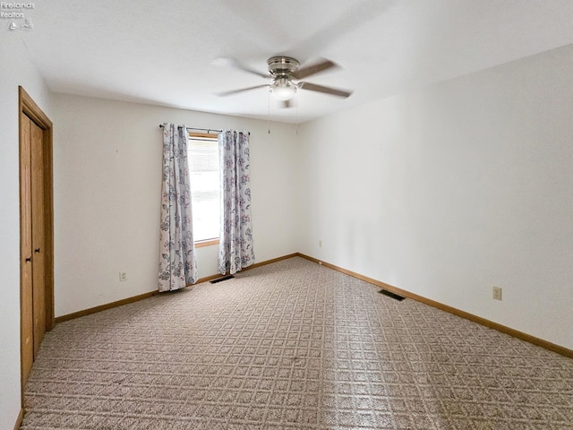 carpeted empty room featuring ceiling fan, visible vents, and baseboards