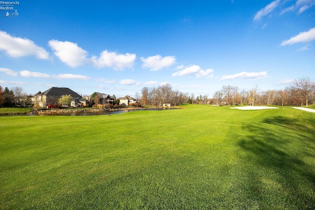 surrounding community with a water view and a lawn