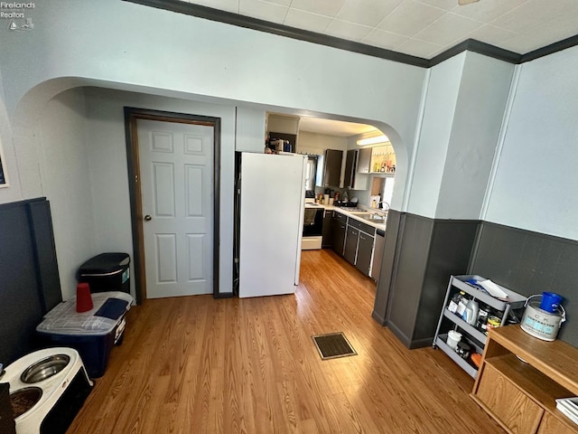 kitchen featuring light wood-type flooring, ornamental molding, white appliances, and sink