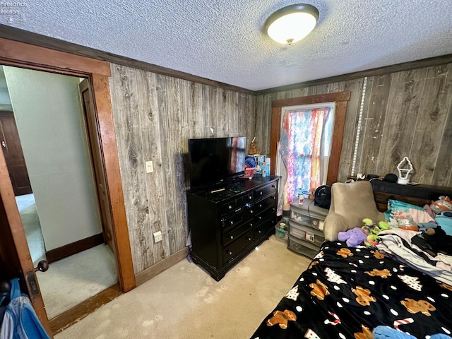 bedroom featuring a textured ceiling, light carpet, and wooden walls