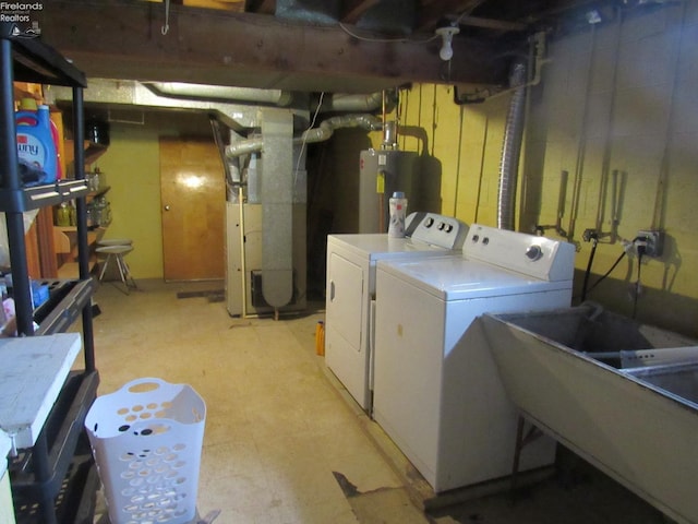 basement with heating unit, sink, water heater, and washing machine and clothes dryer