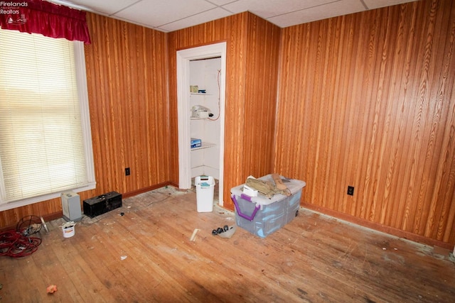 spare room with hardwood / wood-style floors, a drop ceiling, and wood walls