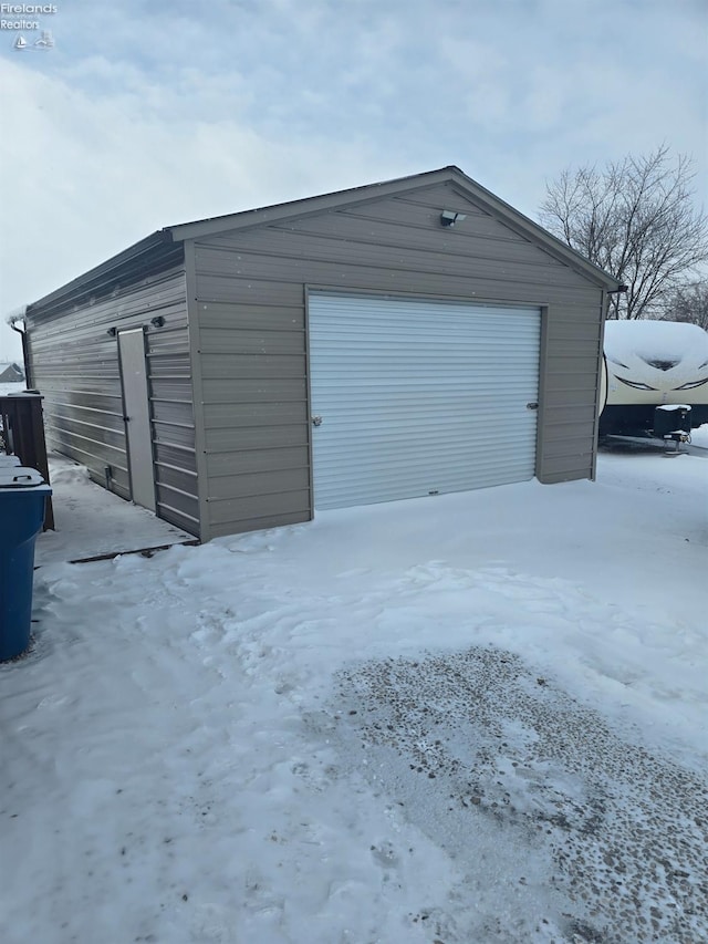 snow covered garage with a detached garage