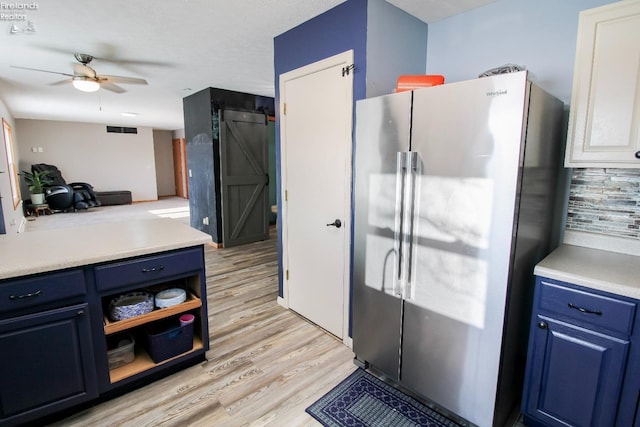 kitchen featuring blue cabinets, a barn door, high end refrigerator, and light countertops