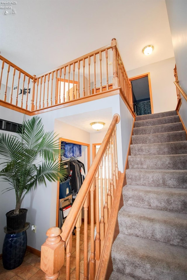 staircase with a towering ceiling and baseboards