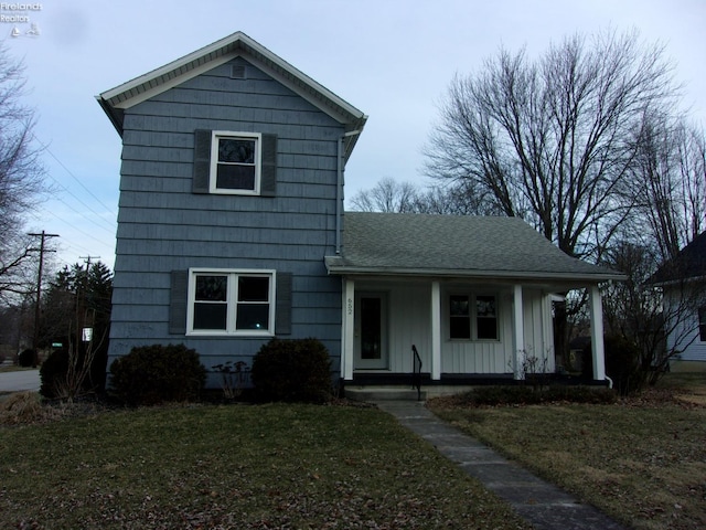 traditional home with a porch, a shingled roof, board and batten siding, and a front lawn