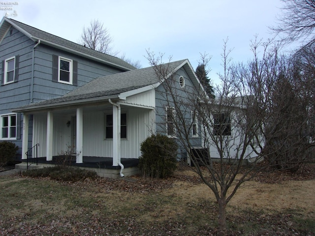 view of front facade with a shingled roof and a porch