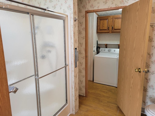 laundry room with washer / clothes dryer, cabinet space, light wood-style flooring, and wallpapered walls