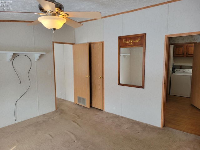 unfurnished bedroom featuring visible vents, washer / clothes dryer, a ceiling fan, and light colored carpet