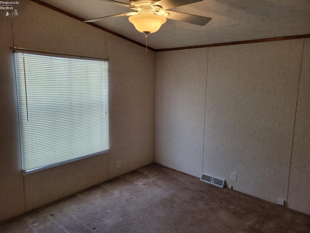 carpeted empty room with visible vents, ornamental molding, vaulted ceiling, ceiling fan, and a textured ceiling