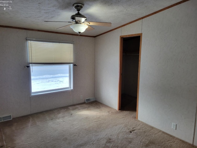 unfurnished bedroom featuring carpet, a textured ceiling, visible vents, and crown molding