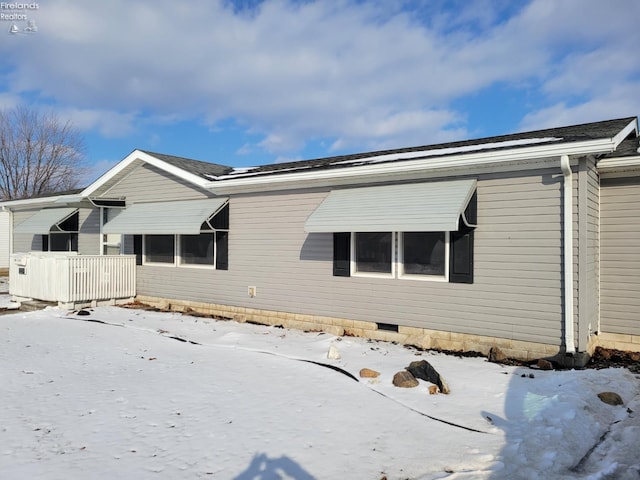 snow covered property with a shingled roof