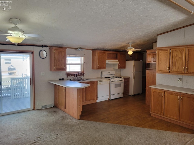 kitchen with under cabinet range hood, white appliances, visible vents, light countertops, and brown cabinetry