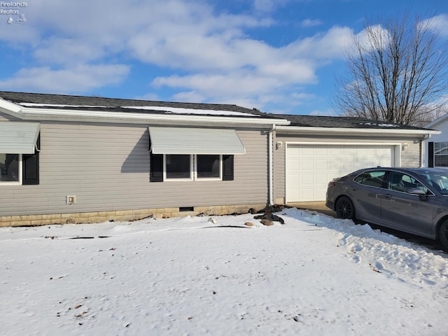 view of snow covered exterior with crawl space and an attached garage