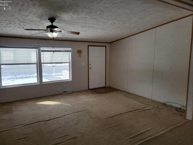 empty room with ornamental molding, carpet, visible vents, and a healthy amount of sunlight