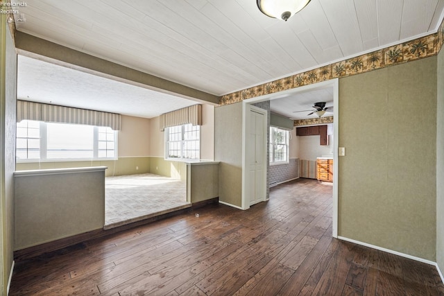 empty room featuring ceiling fan, dark wood finished floors, and a healthy amount of sunlight