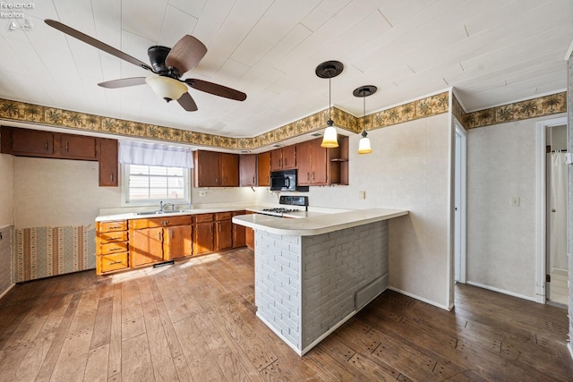 kitchen featuring light countertops, stove, wood finished floors, black microwave, and a peninsula