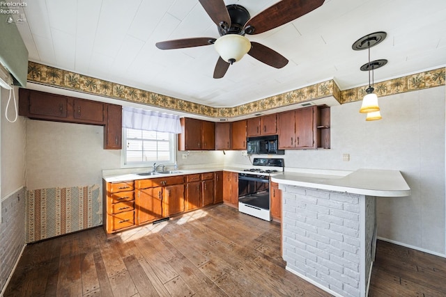 kitchen featuring decorative light fixtures, white gas range, light countertops, a sink, and black microwave