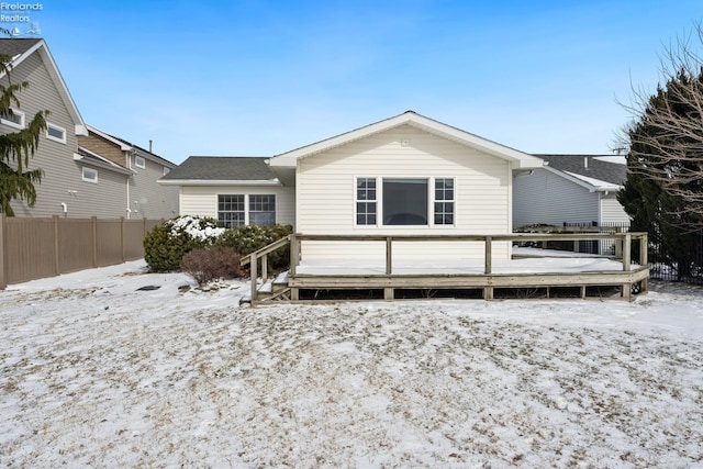 snow covered house featuring fence and a wooden deck