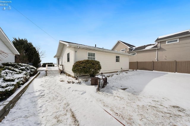 snow covered rear of property with fence