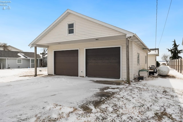 snow covered garage featuring a detached garage