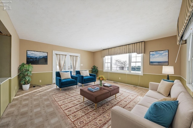 living room with a wainscoted wall and a textured ceiling