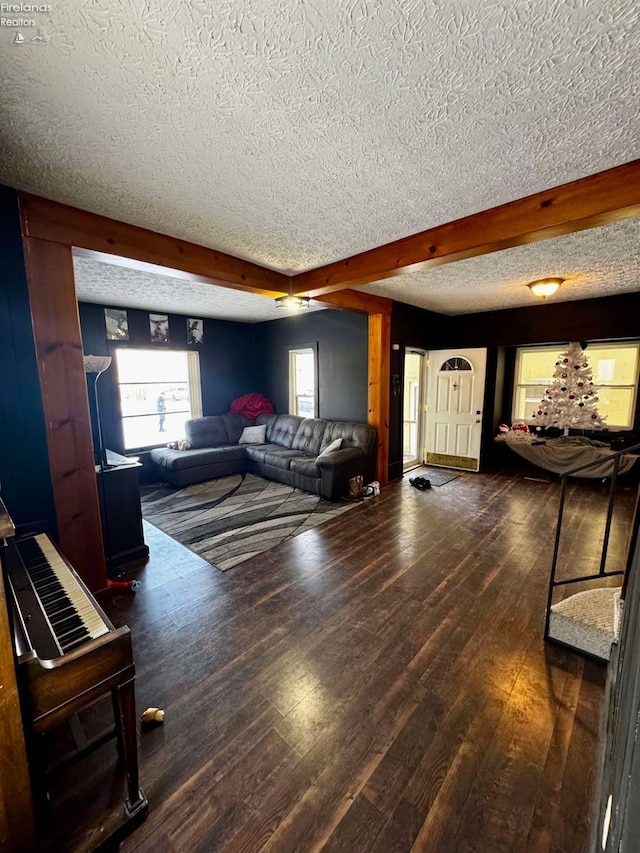 living area with dark wood-style floors, beam ceiling, and a textured ceiling