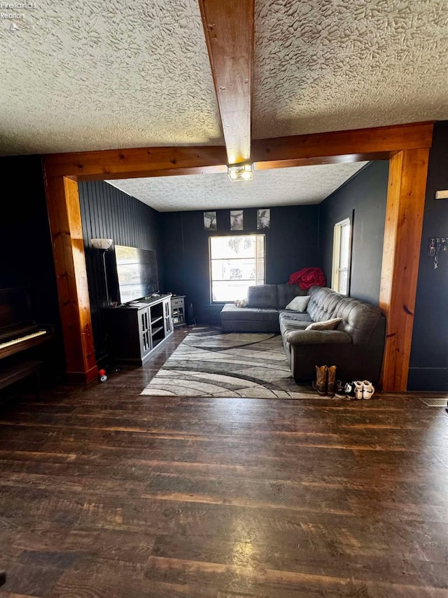 living area featuring a textured ceiling, dark wood finished floors, and beam ceiling