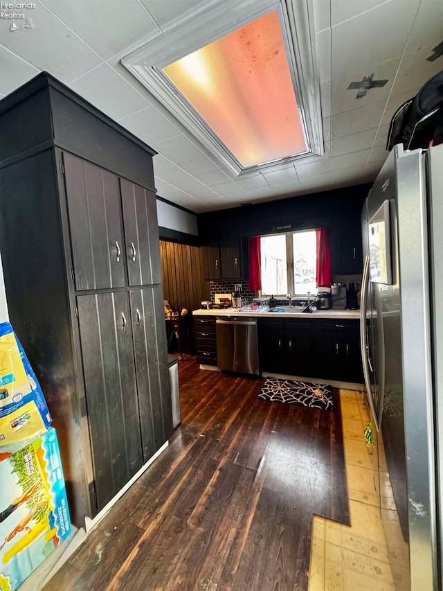 kitchen featuring a sink, stainless steel appliances, dark wood-type flooring, and light countertops