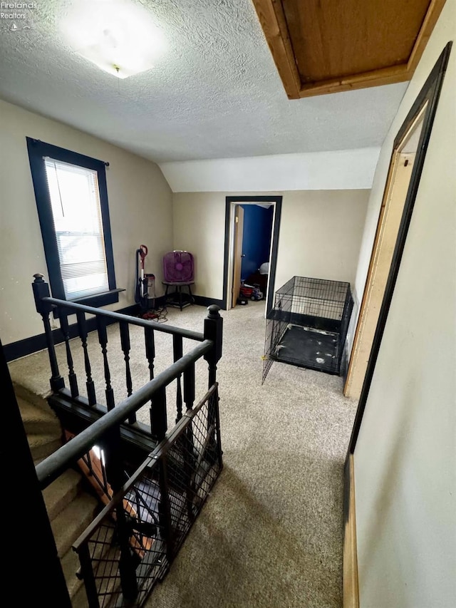 carpeted bedroom featuring lofted ceiling, a textured ceiling, and baseboards