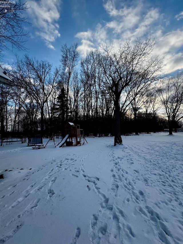 yard covered in snow with a playground