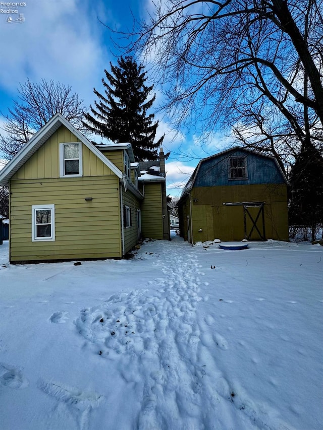 view of snow covered exterior with board and batten siding and a garage