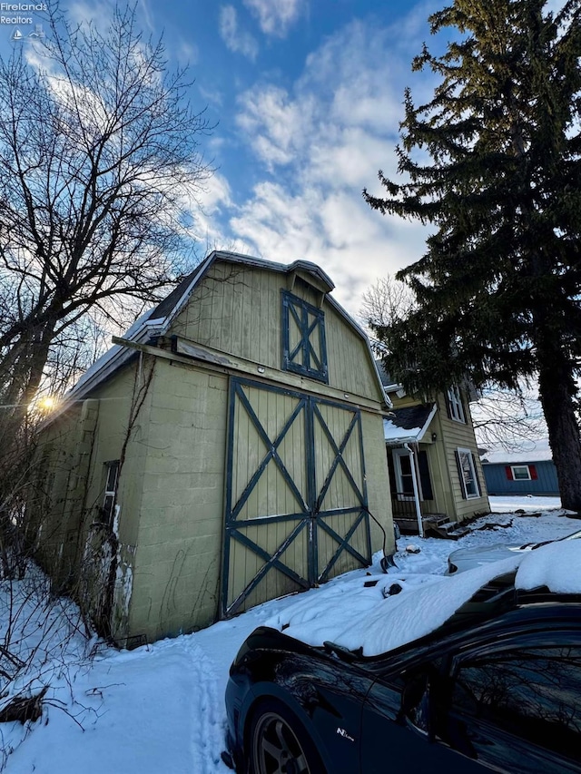 snow covered structure with an outdoor structure and a barn